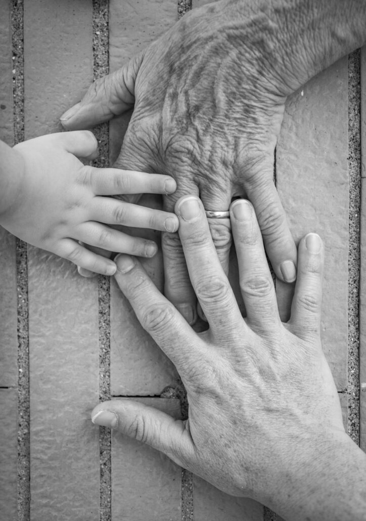 Three hands together, grandmother (elderly woman), mother, daughter, granddaughter. Family unity, love, help, assistance. Age and generational difference. United family.